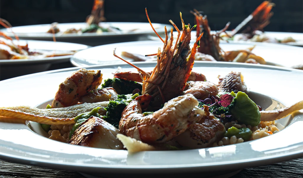 Culinaire presentatie van een verfijnd gerecht met gegrilde garnalen en verse groenten